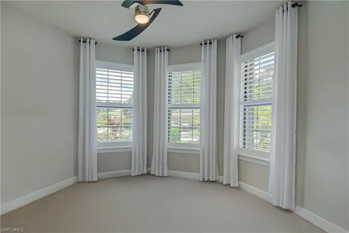 Front bedroom featuring light colored carpet being replaced, healthy amount of natural light, and ceiling fan  - shown empty