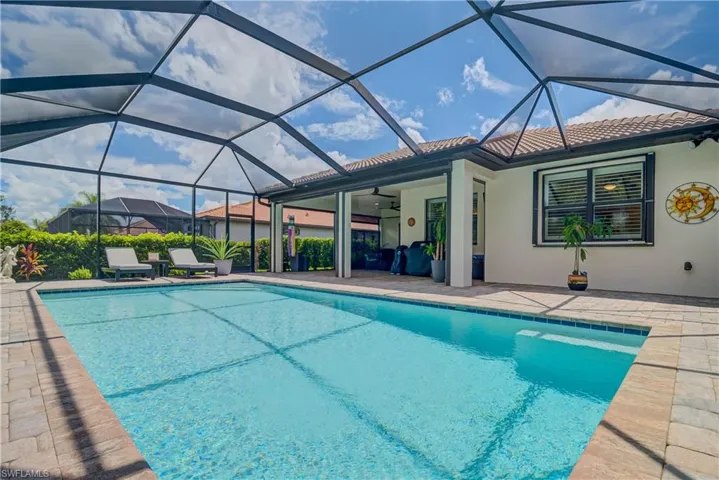 Outdoor heated saltwater pool with a panoramic screen cage featuring Hurricane Shutters and a covered lanai area as well - lush landscaping and outdoor lighting - overlooks two waterways
