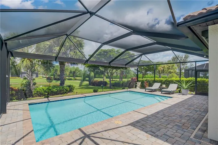 Outdoor heated saltwater pool with a panoramic screen cage featuring Hurricane Shutters and a covered lanai area as well - lush landscaping and outdoor lighting - overlooks two waterways