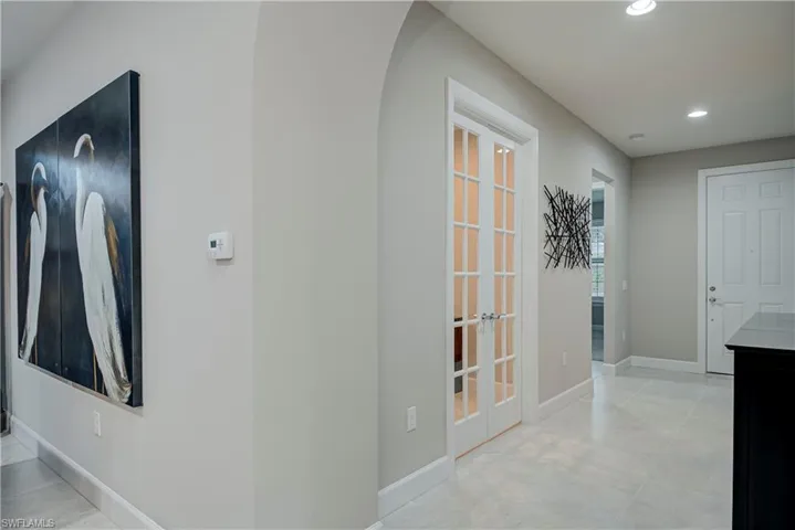 Hallway with french doors to the den, recessed lighting, arched walkways, and light tile patterned floors