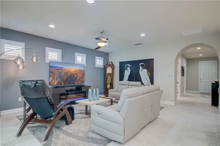 Living area featuring arched walkways, recessed lighting, light tile patterned floors, and ceiling fan