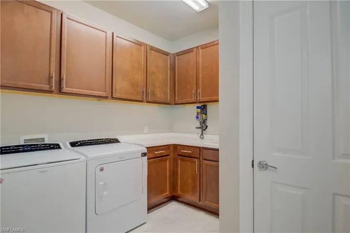 Washroom with independent washer and dryer, light tile patterned floors, and cabinet space- it is huge!