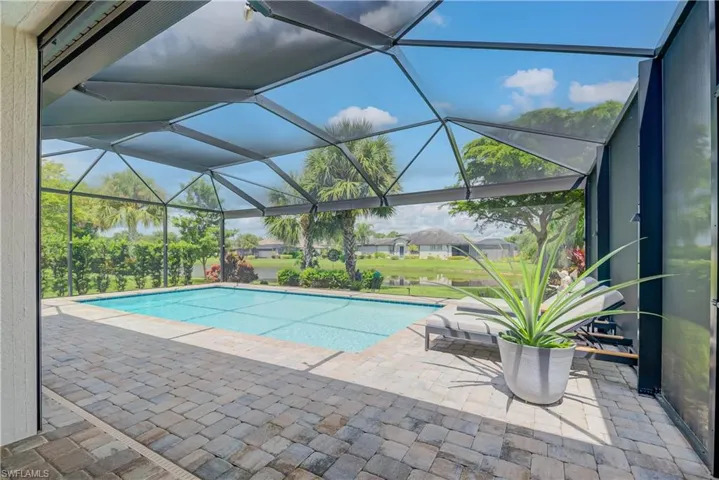 Outdoor heated saltwater pool with a panoramic screen cage featuring Hurricane Shutters and a covered lanai area as well - lush landscaping and outdoor lighting - overlooks two waterways
