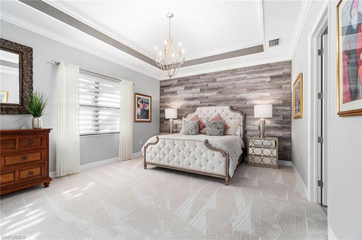 The primary suite exudes a feel of casual elegance with its spaciousness, detail wall, tray ceiling with accent and custom light fixture.