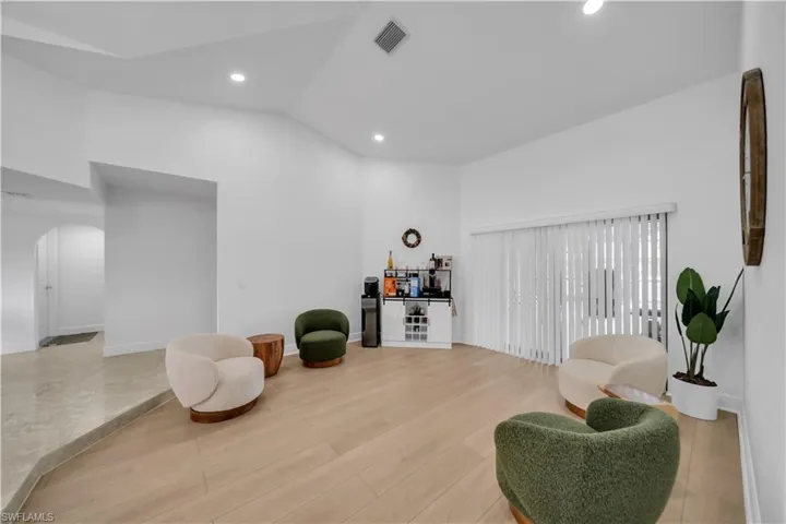Living area with arched walkways, vaulted ceiling, light wood-type flooring, and recessed lighting