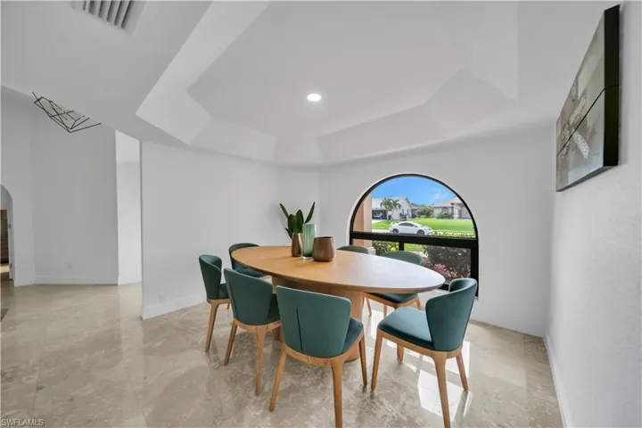 Dining room featuring arched walkways, a raised ceiling, and recessed lighting