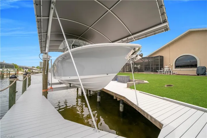 Dock area with boat lift, a lawn, and a water view
