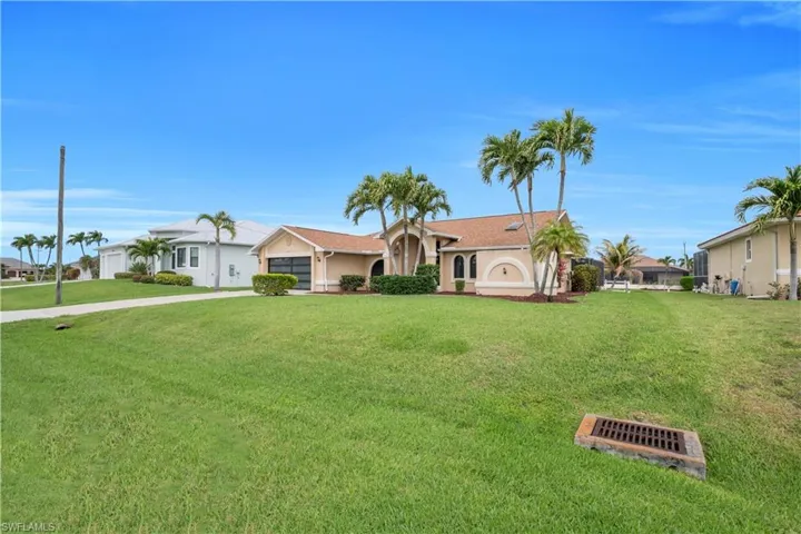 Ranch-style home with a garage, driveway, a front lawn, and stucco siding