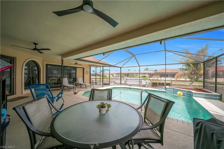 Swimming pool with a patio area, a sunroom, glass enclosure, and outdoor dining area