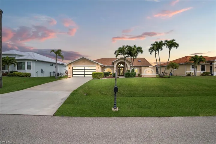 Ranch-style house featuring driveway, stucco siding, a yard, and an attached garage
