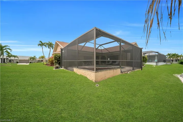 Back of property featuring glass enclosure, a sunroom, a yard, and an outdoor pool