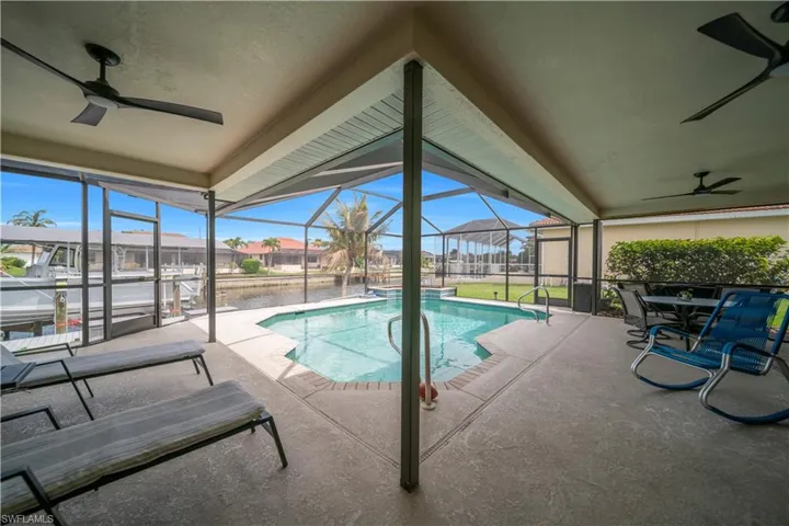 Outdoor pool with a sunroom, glass enclosure, a patio, a residential view, and outdoor dining area