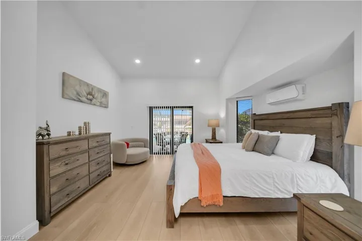 Bedroom featuring light wood finished floors, access to outside, lofted ceiling, and recessed lighting