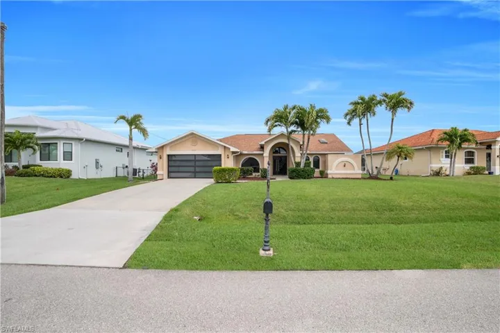 View of front facade with a front yard, stucco siding, driveway, and a garage