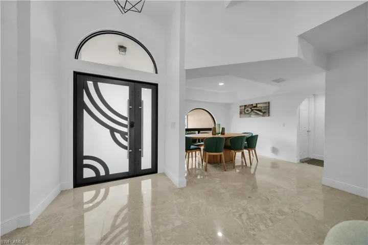 Foyer entrance featuring arched walkways, a raised ceiling, and recessed lighting