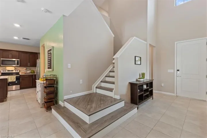 Staircase featuring a towering ceiling and light tile floors