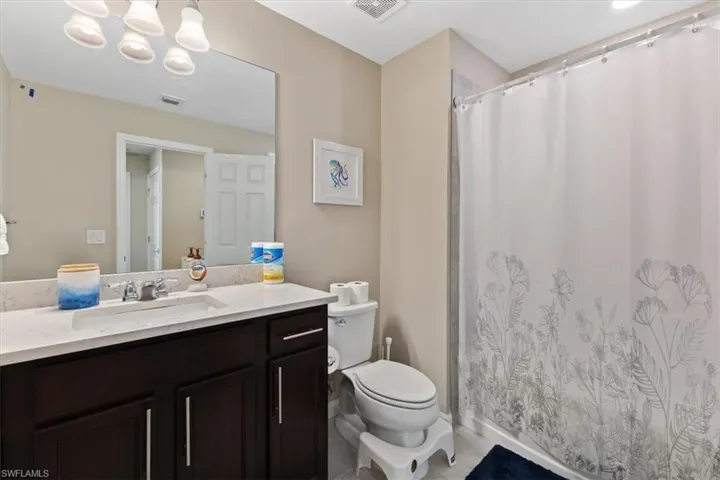 Bathroom featuring a notable chandelier, tile flooring, toilet, and vanity