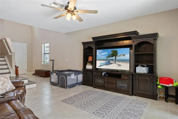 Living room featuring light tile flooring and ceiling fan