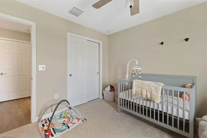 Bedroom featuring a nursery area, a closet, ceiling fan, and carpet floors