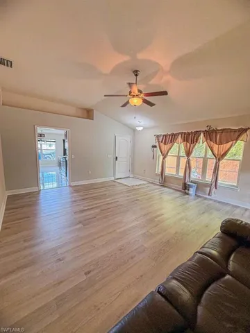 Unfurnished living room featuring a ceiling fan, light wood-style floors, and lofted ceiling