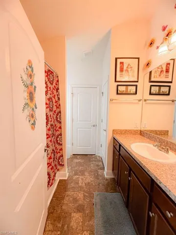Bathroom featuring curtained shower, vanity, and stone finish flooring