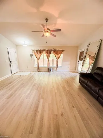 Unfurnished living room featuring light wood-style floors, ceiling fan, and lofted ceiling