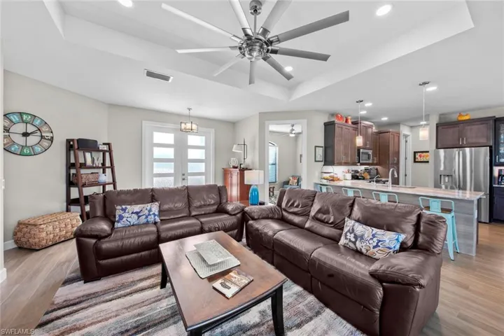 Living room with french doors, light hardwood / wood-style floors, a raised ceiling, and sink