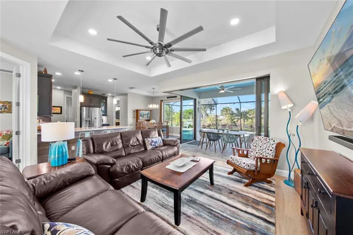 Living room featuring a tray ceiling, ceiling fan, and light wood-type flooring