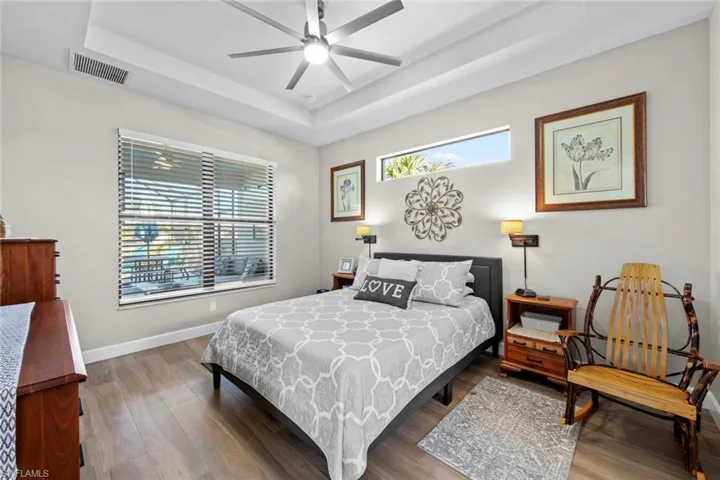Bedroom featuring a raised ceiling, ceiling fan, and wood-type flooring