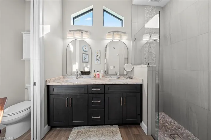 Bathroom featuring vanity, toilet, and a tile shower