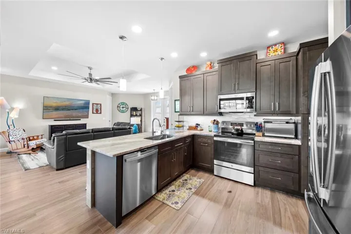 Kitchen featuring dark brown cabinets, kitchen peninsula, sink, and appliances with stainless steel finishes
