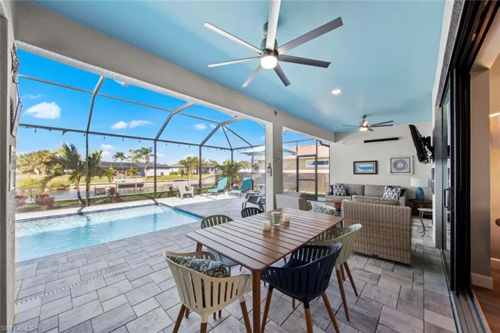 View of pool with glass enclosure, a patio area, ceiling fan, and an outdoor hangout area