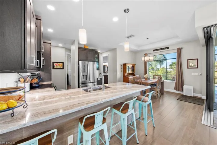 Kitchen with dark brown cabinetry, sink, a raised ceiling, stainless steel fridge, and a breakfast bar area