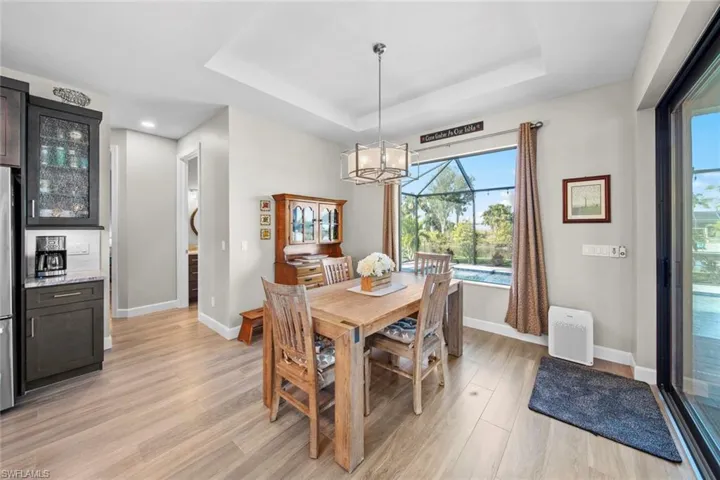 Dining room featuring an inviting chandelier, light wood-type flooring, and a tray ceiling