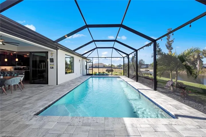View of swimming pool with glass enclosure, ceiling fan, and a patio