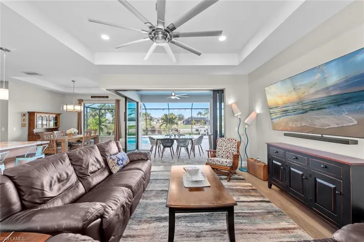 Living room with a tray ceiling, a healthy amount of sunlight, and light wood-type flooring