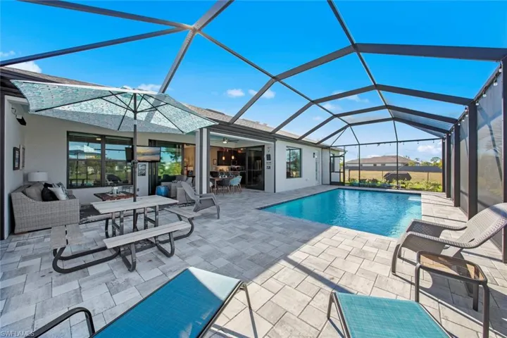 View of pool featuring glass enclosure, ceiling fan, and a patio