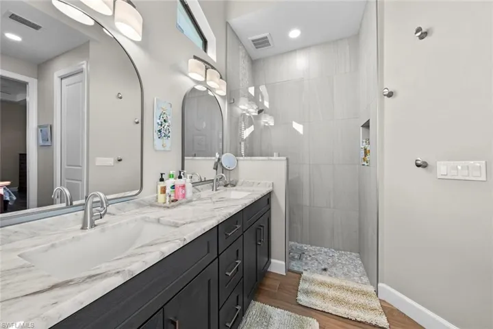 Bathroom with tiled shower, vanity, and hardwood / wood-style flooring