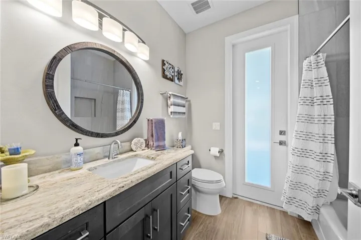 Full bathroom with vanity, toilet, wood-type flooring, and shower / bath combo with shower curtain