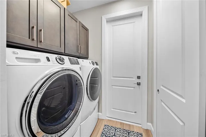 Clothes washing area featuring cabinets, light wood-type flooring, and independent washer and dryer