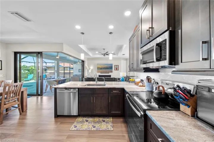 Kitchen featuring kitchen peninsula, sink, stainless steel appliances, and dark brown cabinets