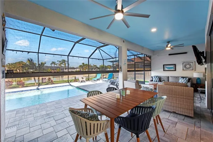 View of pool with a patio, an outdoor hangout area, glass enclosure, and ceiling fan