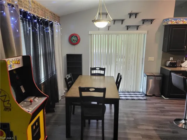 Dining space with dark wood-type flooring and vaulted ceiling