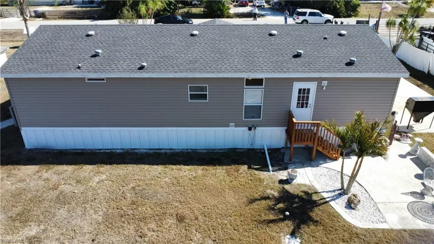 Back of house with roof with shingles and a yard