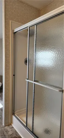 Bathroom with a stall shower and wallpapered walls
