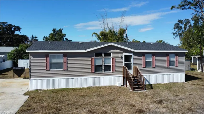 Manufactured / mobile home with a front yard and a shingled roof