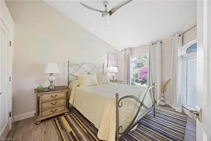 Bedroom with ceiling fan, wood finished floors, lofted ceiling, and baseboards