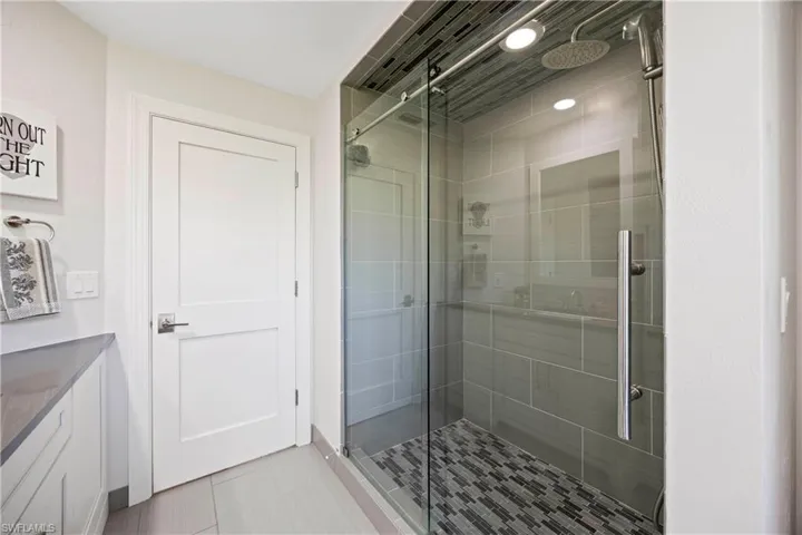 Bathroom featuring tile patterned floors, vanity, and a shower stall