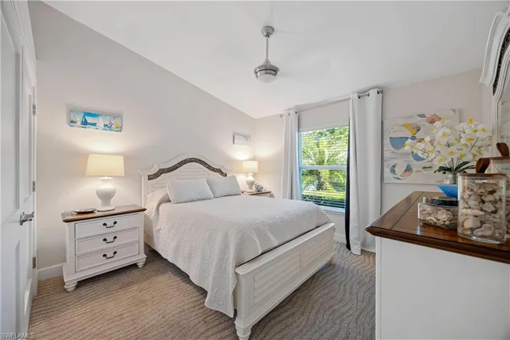 Bedroom featuring baseboards, light carpet, and lofted ceiling