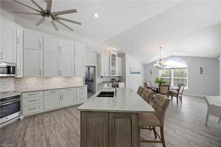 Kitchen featuring a kitchen breakfast bar, white cabinets, light wood-style flooring, a sink, and appliances with stainless steel finishes